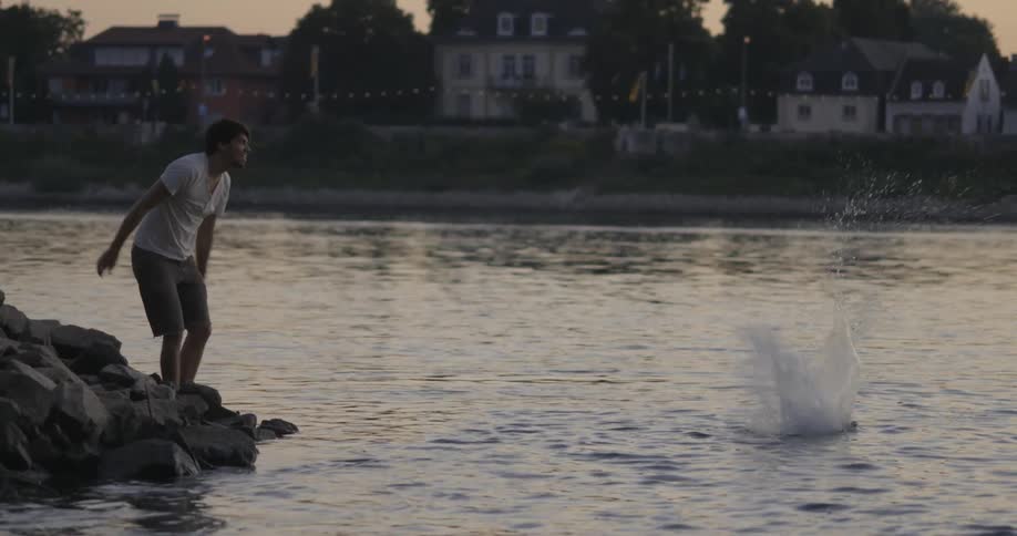 A man tosses a large stone into the water