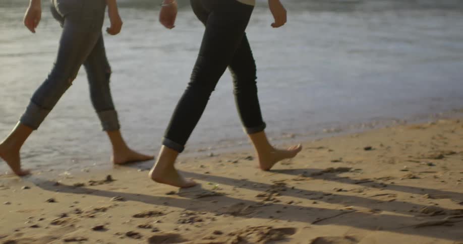 Two people walk together past the water