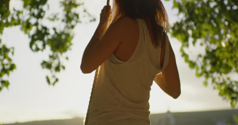 Woman stands on a swing next to a lake