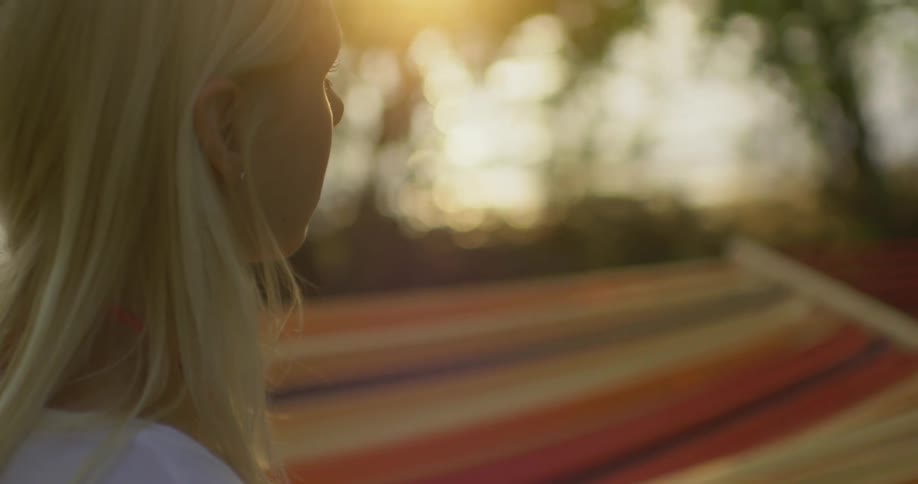 A woman stands beside a hammock blowing in the wind
