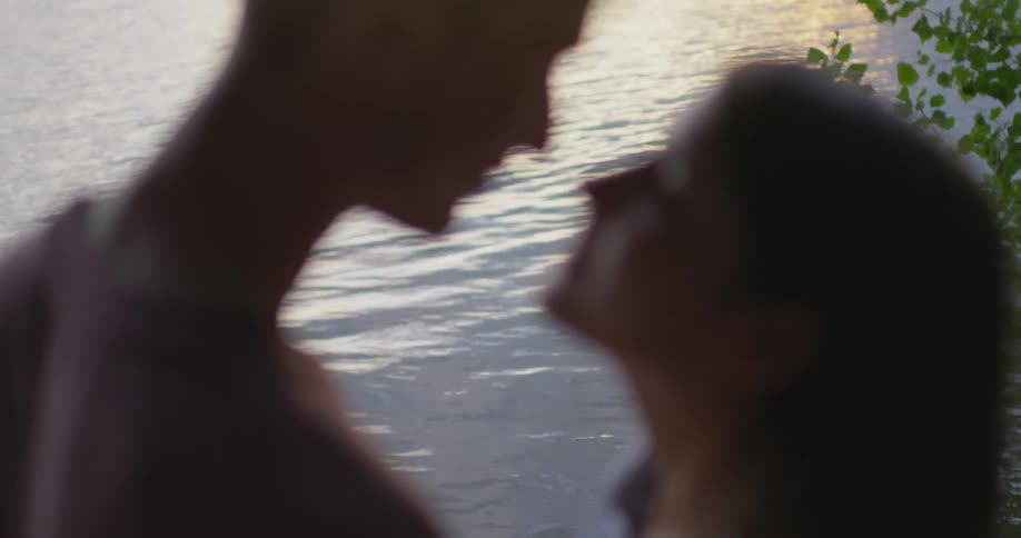 A man and woman kiss by the water