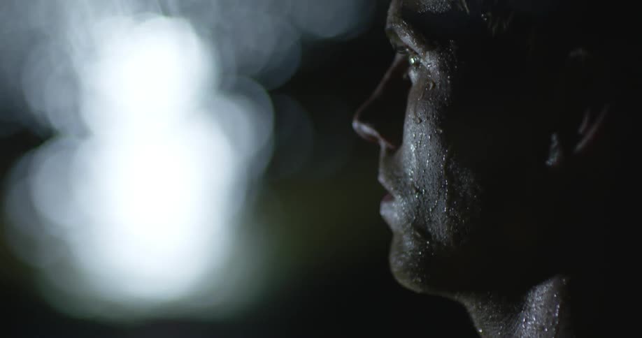 Light shines near a man's wet face