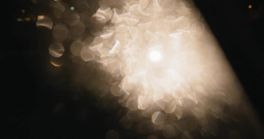 Someone walks in front of a light with the camera blurry due to water droplets on the lens