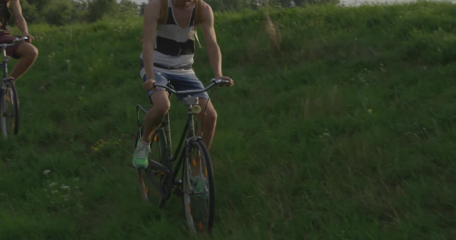 A boy lifts his feet off the pedals as he rides his bike down a grassy hill