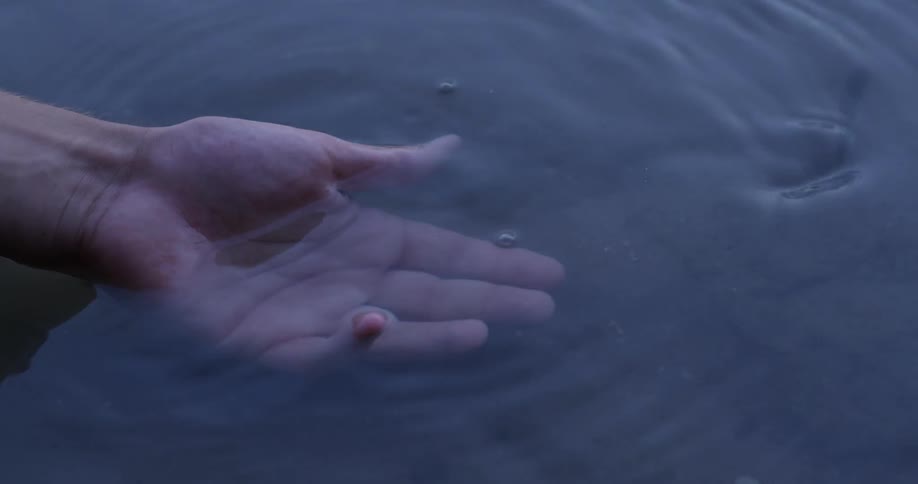 Person dunks their hand in a rippling pool of water