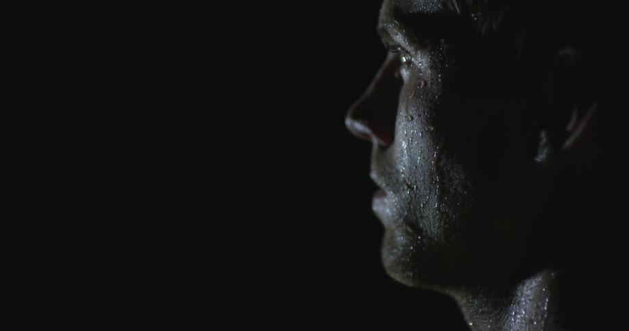Sweaty faced man stares into a bright light at night