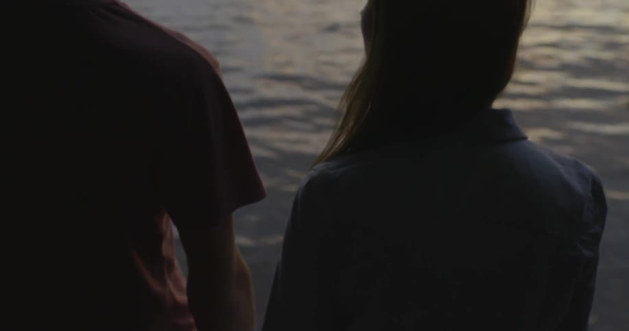 Man and woman hold hands by a lake