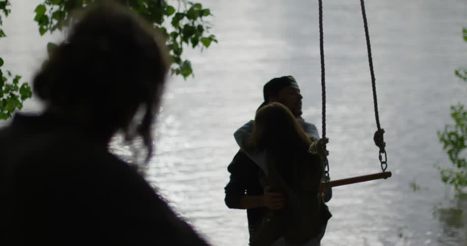 A man helps a woman from a swing