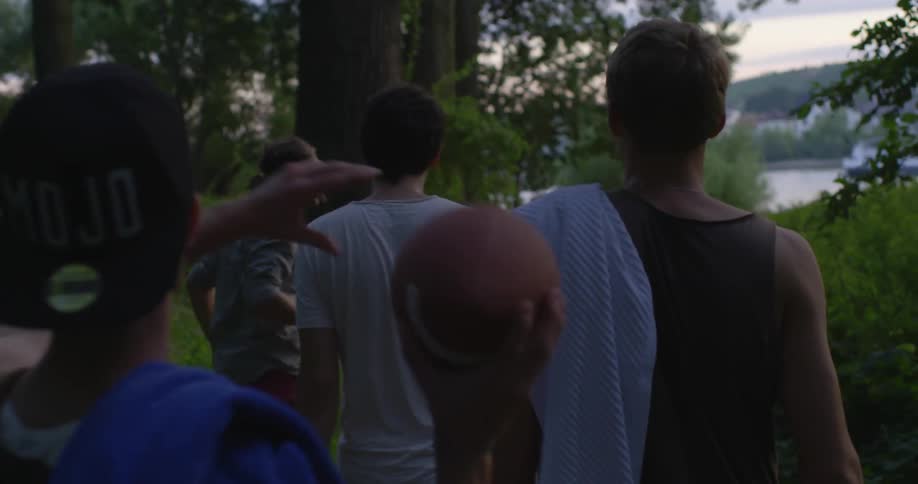 A group of people walk towards the water throwing around a football