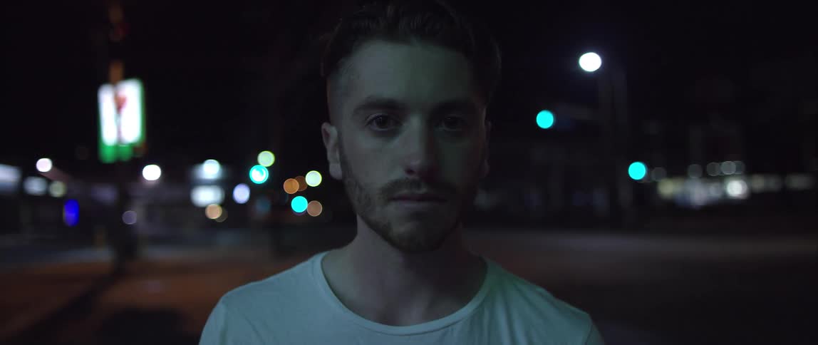 Man in a white shirt standing outside in the dark