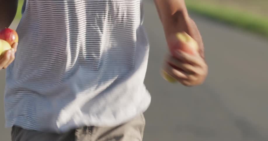 A man is running outside with apples