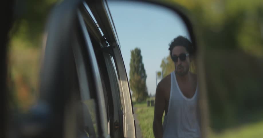 A man is running to jump into a moving vehicle on a sunny day
