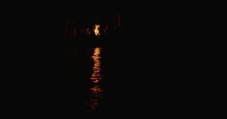 People sit around a campfire burning at night