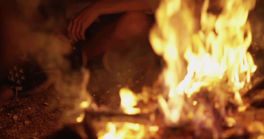 People sit next to a campfire at night