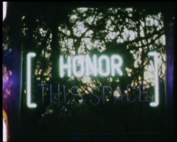 A neon sign is glowing in a window during the day
