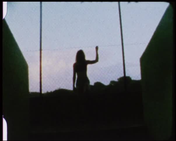 Woman stands with her hand on a chain link fence