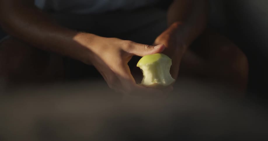 A man holds a partially eaten green apple