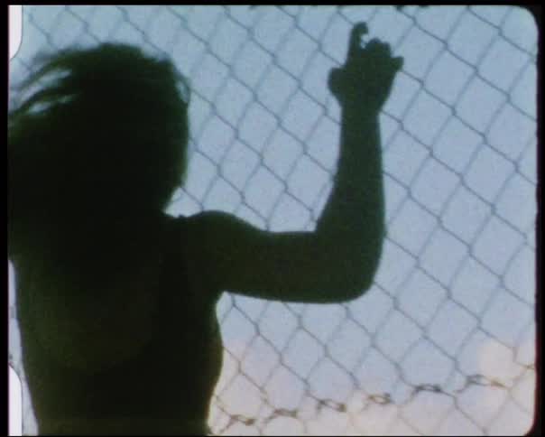 A woman shakes a chain link fence