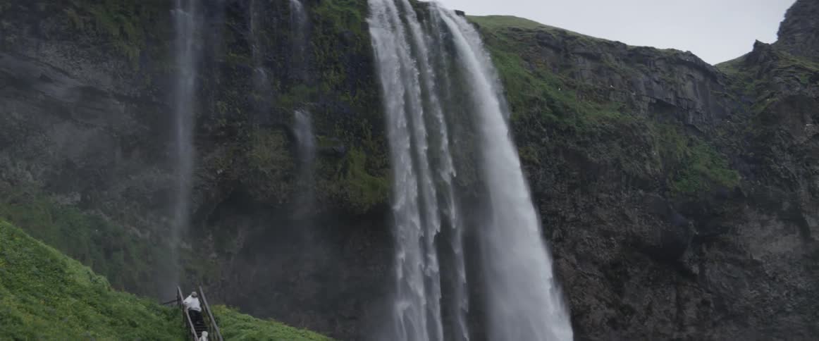 Water cascades down from several places along the edge of a cliff