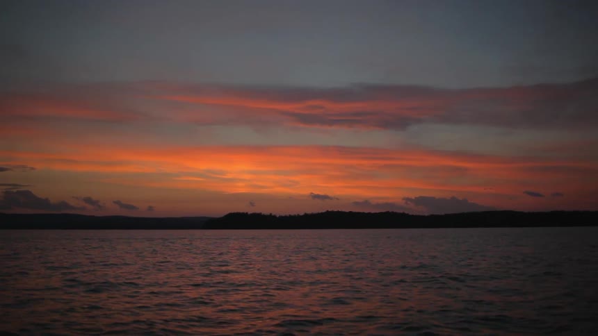 An orange sunset as seen from a boat in the ocean