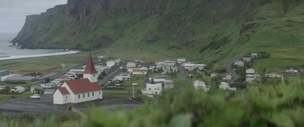 A village sits near the coast at the foot of a hill