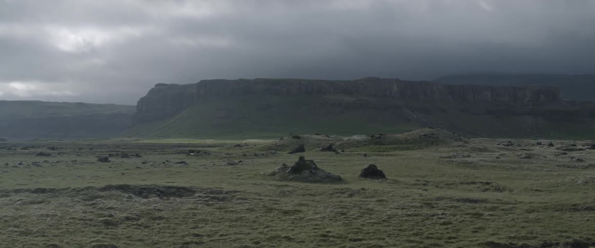 Storm clouds hang over a mountain valley during the day