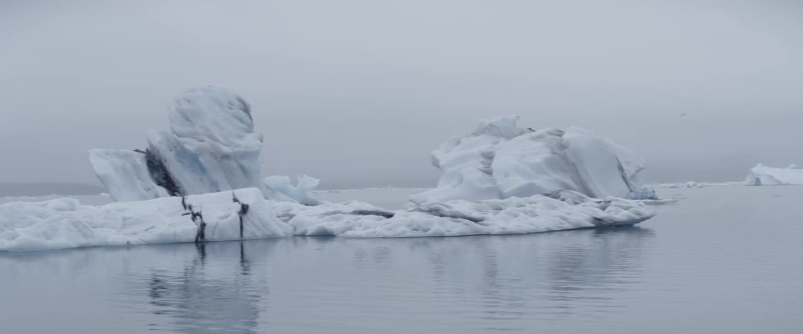 Icebergs are floating in the ocean on a cloudy day