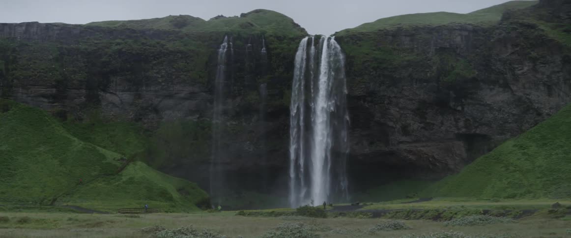 Water falls off the side of a tall cliff