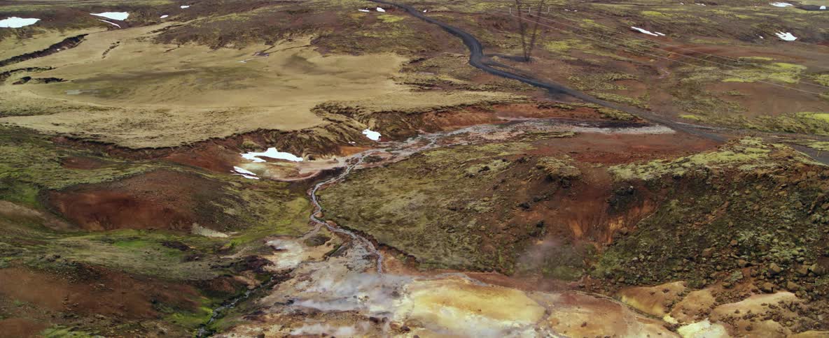 Steam is rising from hot springs in a natural landscape on a cold day