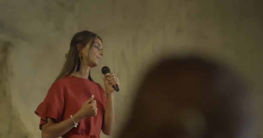 A woman holding a microphone talks to an audience
