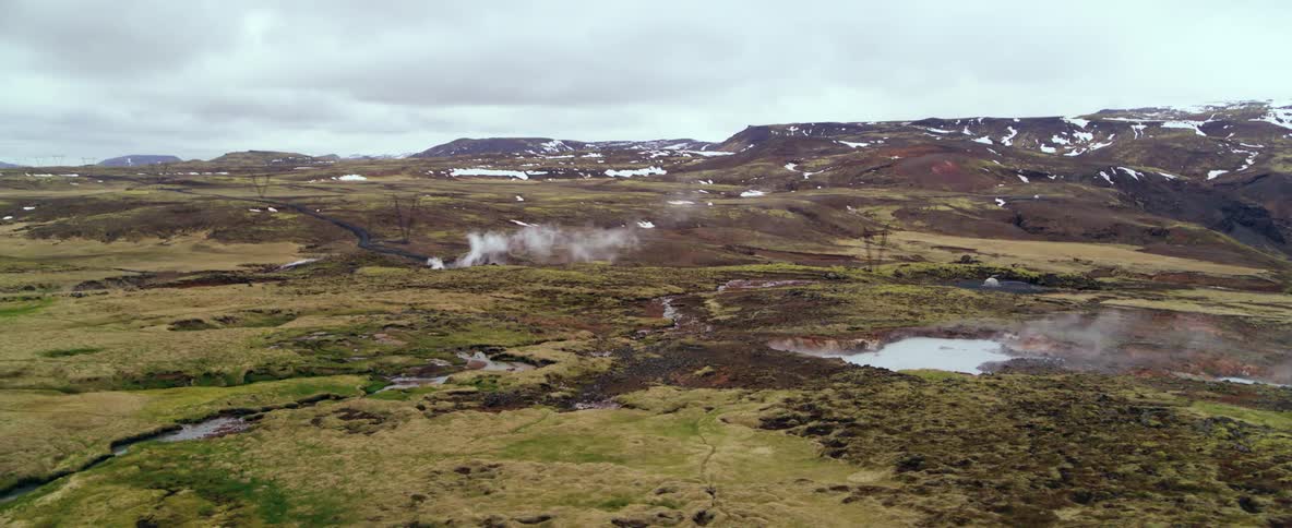 Steam is rising from hot springs in a natural landscape on a cold day