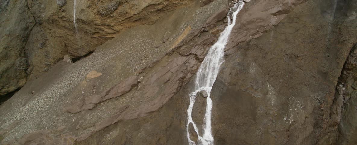 Waterfalls are cascading over bare cliffs during the day