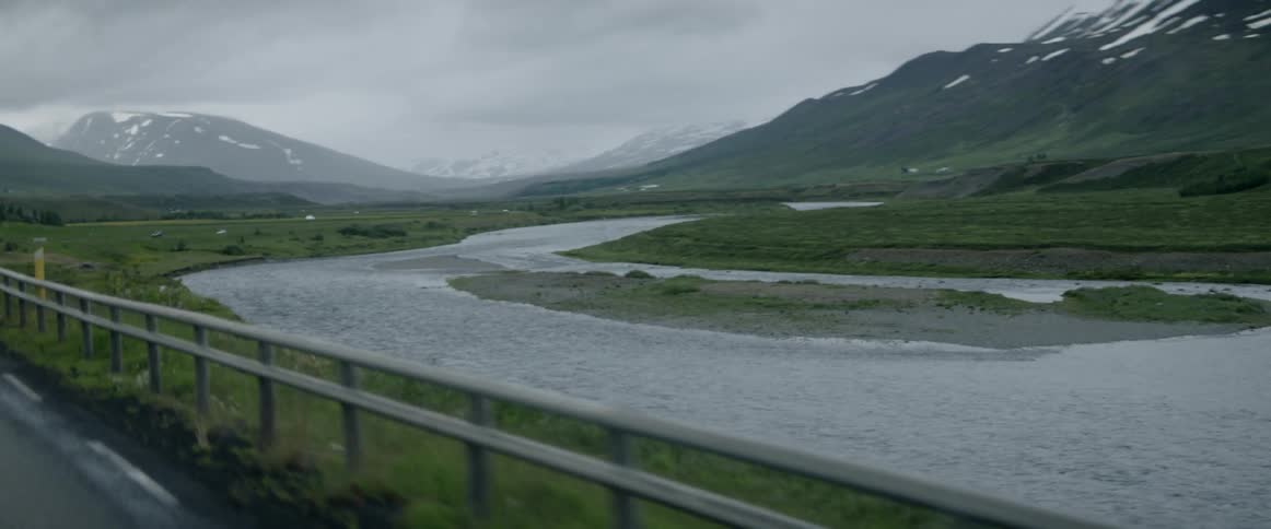 A car rides past the side of a mountain range