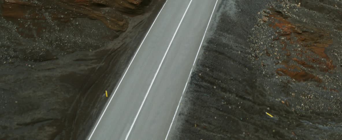 A road is winding through the tundra in a natural landscape during the day