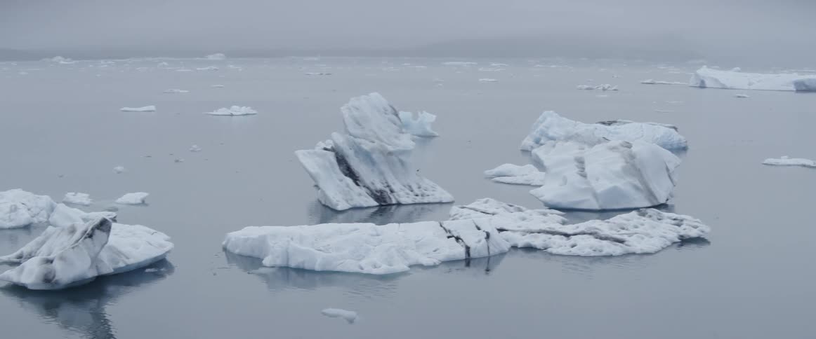 Icebergs are floating in the ocean on a cloudy day