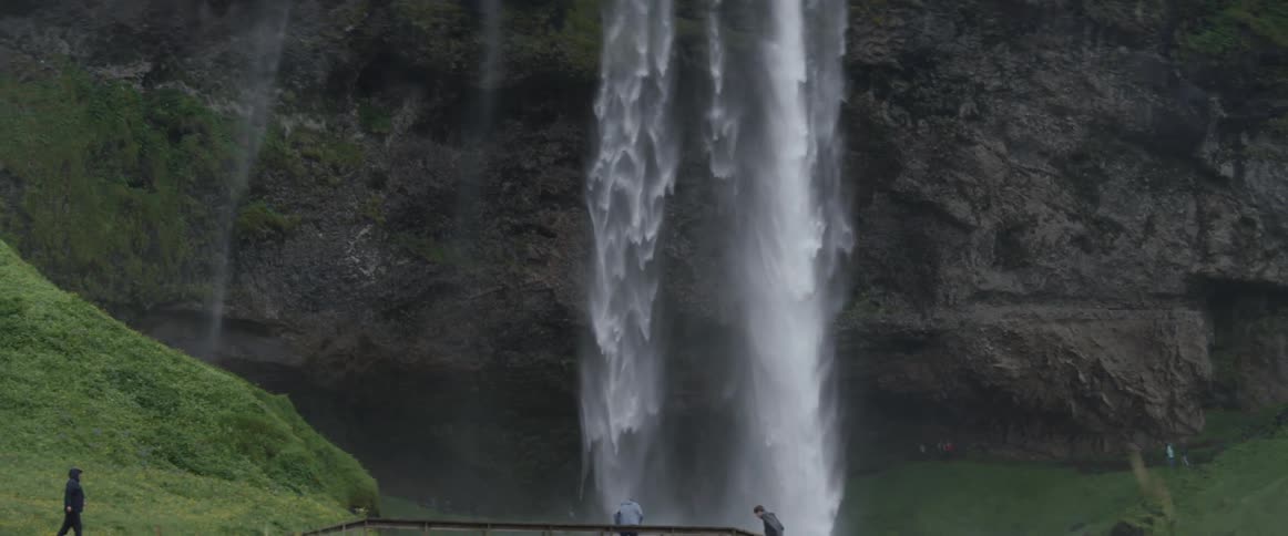 A waterfall is cascading into a pool at the bottom of cliffs during the day