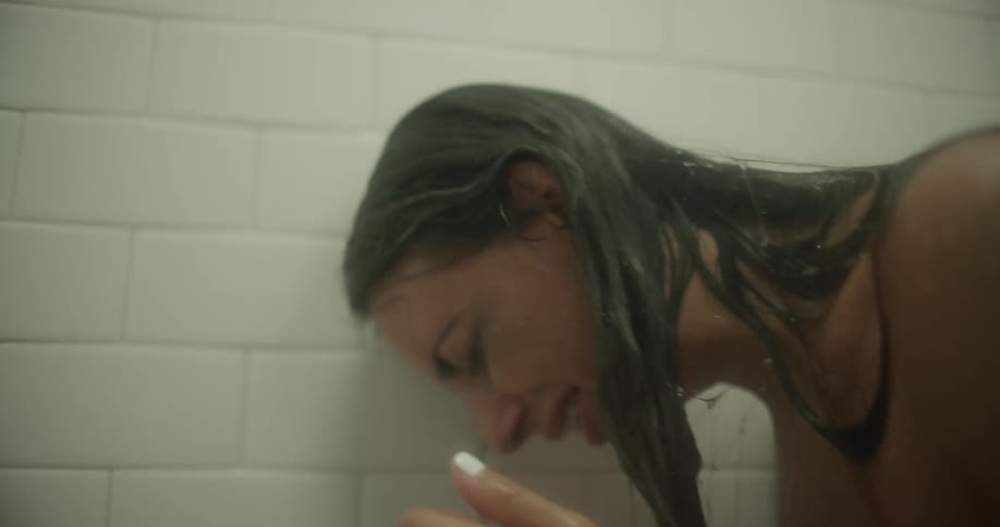 A woman is sitting in a shower crying
