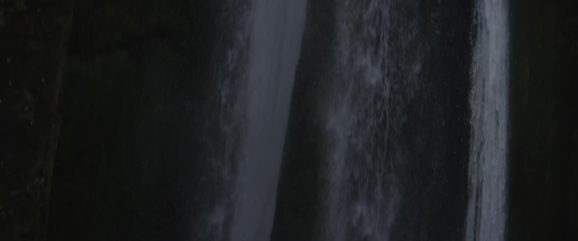 A waterfall is cascading over a cliff during the day