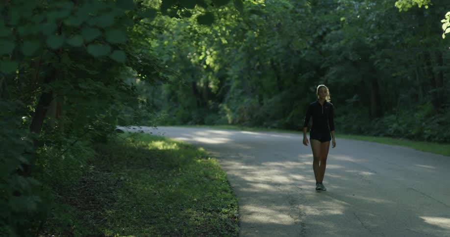 A woman walking down a road is turning around and adjusting her hair
