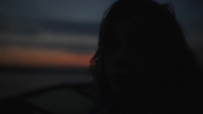 A woman stands outside at sunset