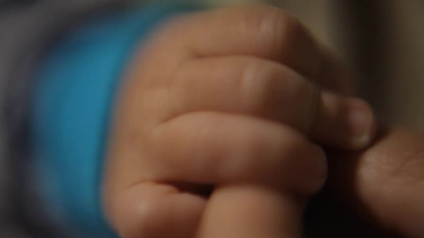 A person holds the hand of a baby