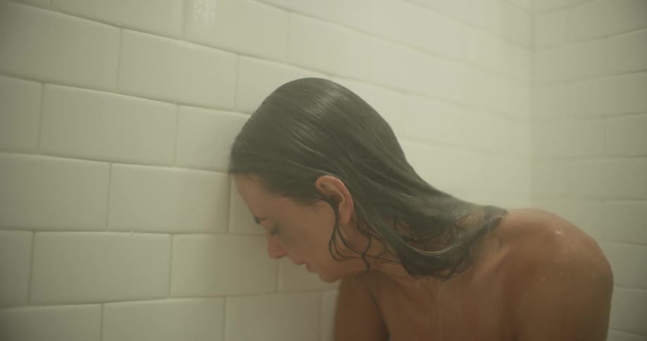 A woman is showering and crying at the same time