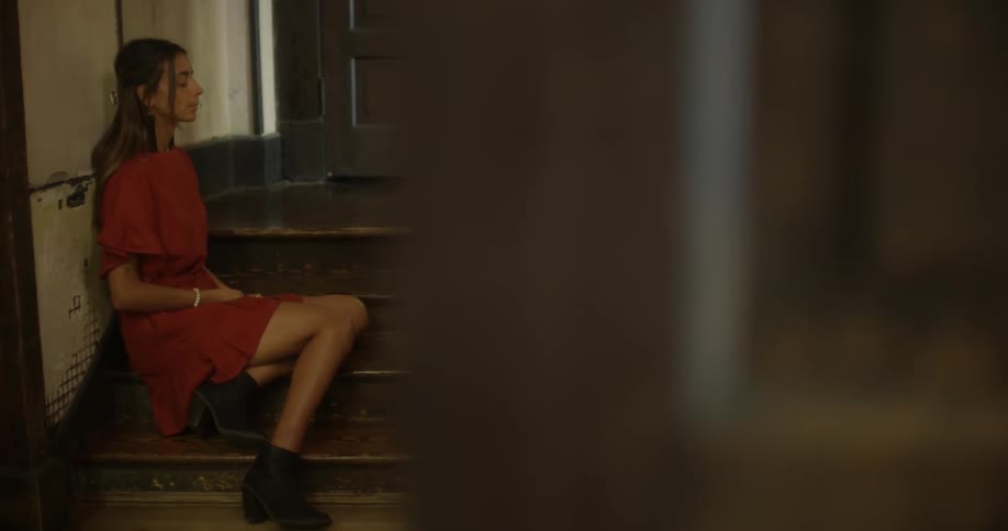 A woman in an orange dress sits on the stairs