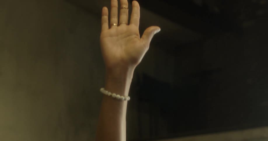 A woman is raising her hand as she is giving a speech during the day