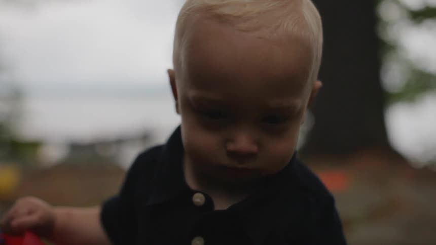 A toddler is standing outside in a natural setting during the day
