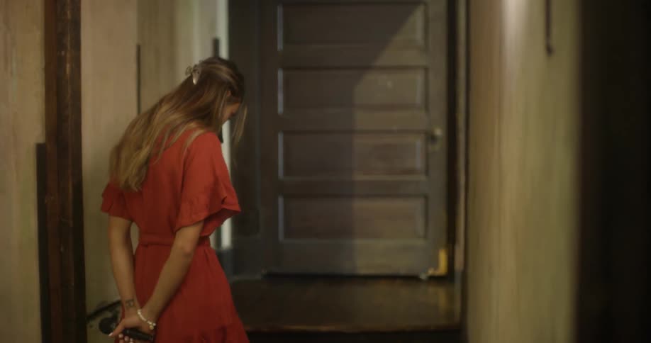 A woman paces in a hallway with a microphone in hand
