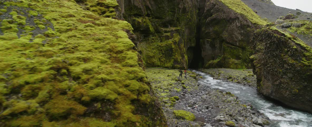 People walking next to a creek running through a rocky wilderness
