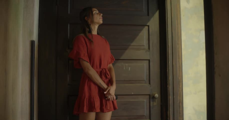 A woman in an orange dress walks through a doorway