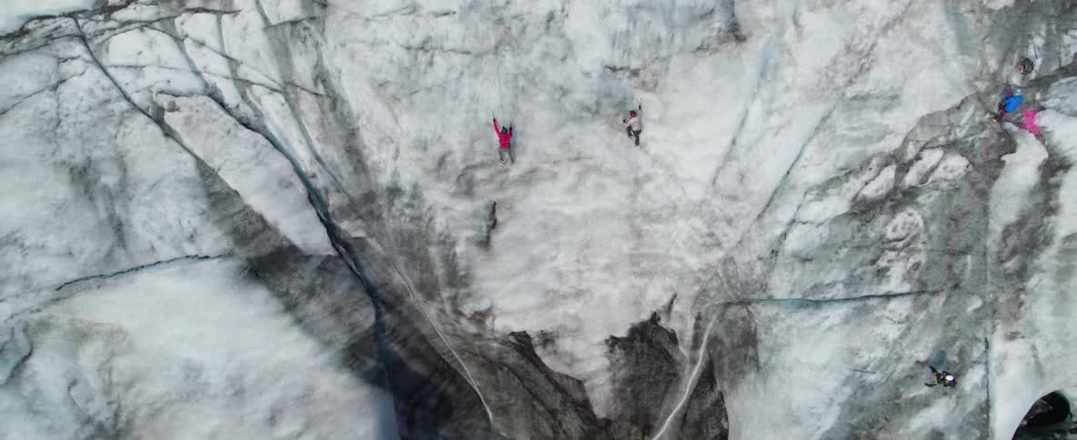 People climb an ice covered cliff