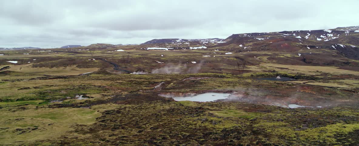 Steam is rising from hot springs in a natural landscape on a cold day